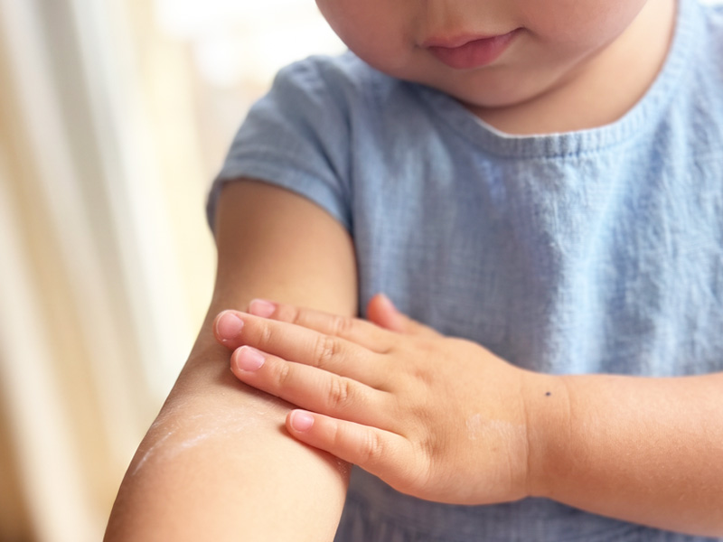 子どもが腕にベビーパウダーをつけている様子